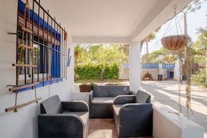 A covered outdoor seating area with wicker furniture, a view of the street, and a hanging plant. - Holiday Home 'Villa La Mayorazga Cozy Cottage' with Private Pool, Private Terrace and Wi-Fi (Pago del Humo)