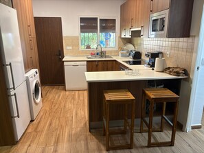 Eine moderne Küche mit Holzschränken, einem eingebauten Geschirrspüler, einer Mikrowelle und einem großen Fenster.