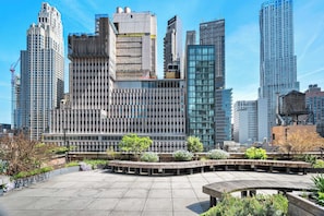 A modern urban plaza with a variety of buildings, including a large glass-fronted structure and a building with a grid-like facade. - 17john: Luxury 3 Bed W/D in Unit + GYM + Lounge (New York)
