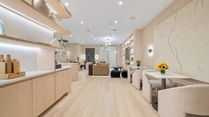 A modern kitchen with wooden cabinets, a marble countertop, and a dining area with a sofa and table. - 17john: 3 Bed Private Terrace W/D in Unit + GYM (New York)
