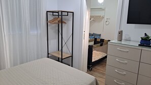 Une chambre à coucher comprenant un lit, une commode avec des tiroirs, une armoire et une table de chevet.