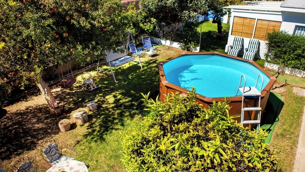 Un giardino sul retro con piscina, altalena e un piccolo spazio attrezzato con patio.