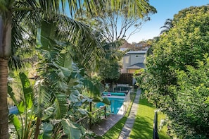 A residential backyard with a swimming pool, lush greenery, and a house in the background. - South Coogee Sanctuary | Pool, Space & Sea Air (South Coogee)