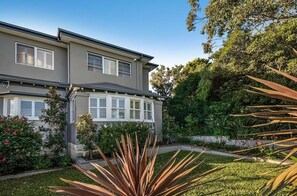 Une maison à deux étages avec un jardin à l’avant.