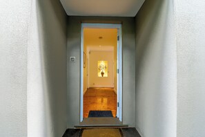 A hallway with a wooden floor leading to a room with a door at the end. - South Coogee Sanctuary | Pool, Space & Sea Air (South Coogee)