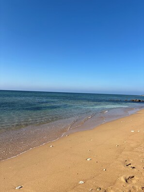 Ein Strand mit klarem, blauem Wasser und einem sandigen Ufer.