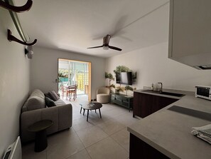 A modern living space with a sofa, a coffee table, a TV, and a kitchen area. - Access to La Cotinière Beach—La Cabane de Philippine (Saint-Pierre-d'Oléron)