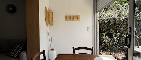 Un coin repas avec une table et des chaises en bois, un vase et un luminaire fixé au mur.