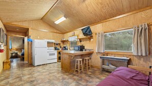 Eine kompakte Küche mit Kühlschrank, Herd, Mikrowelle und Barhockern.