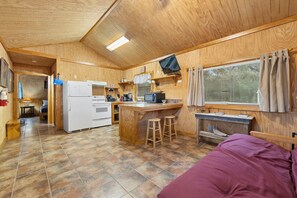 A compact kitchen with a refrigerator, stove, microwave, and bar stools. - Casita: 1  BR, 1  BA House in Concan, Sleeps 4 (Concan)