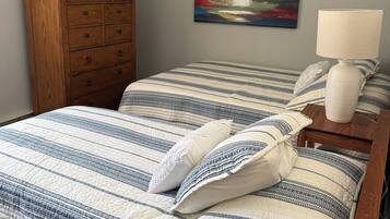 Un dormitorio con una cama, un aparador de madera, un cuadro y una lámpara de noche.