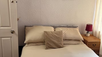 Une chambre d’hôtel avec un lit, une table de chevet avec une lampe et trois tableaux encadrés au mur.