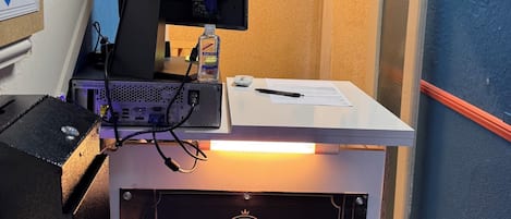 A reception desk with a monitor, a water bottle, and a sign indicating the reception area.