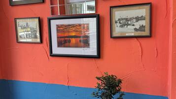 Eine Wand mit mehreren gerahmten Fotografien und ein kleiner Tisch mit einer Bonsai-Pflanze.