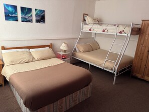 A room with a single bed, a bunk bed, a nightstand with a lamp, and a wooden cabinet. - MIRAGE HOTEL (Blackpool)