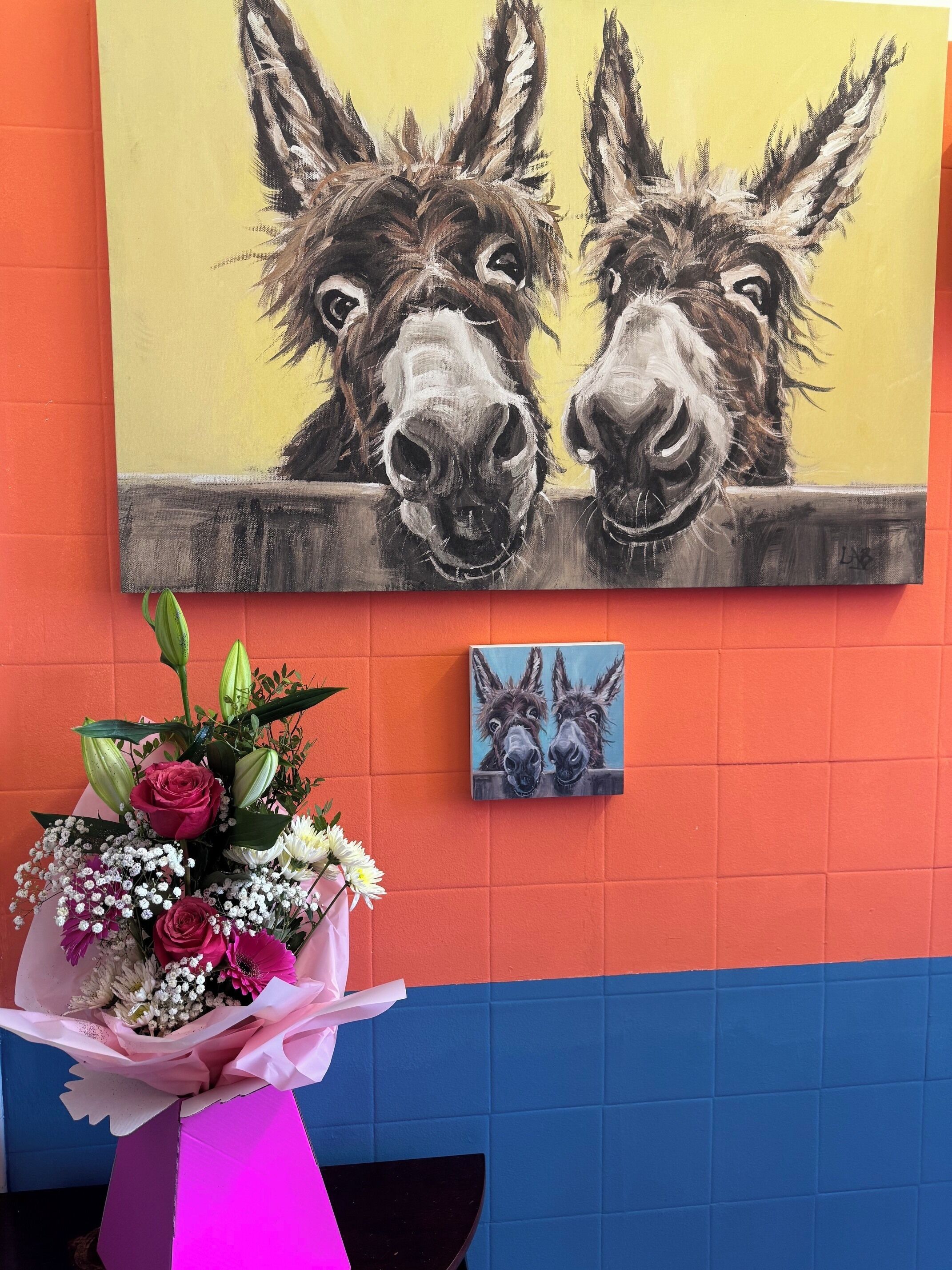 Una pared con un cuadro de burros y un cuadro más pequeño con dos burros.