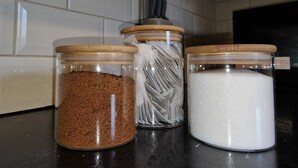 Tres frascos de vidrio con tapas de madera sobre una encimera de cocina.