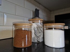 Trois bocaux en verre avec des couvercles en bois, posés sur un plan de travail de cuisine.