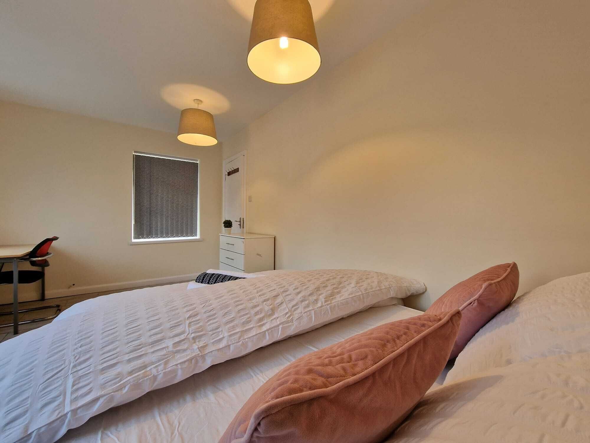 Un dormitorio con dos camas, una ventana, un escritorio y una silla.