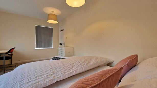Un dormitorio con dos camas, una ventana, un escritorio y una silla.