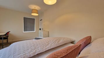 Un dormitorio con dos camas, una ventana, un escritorio y una silla.
