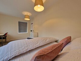 Une chambre avec deux lits, une fenêtre, un bureau et une chaise.