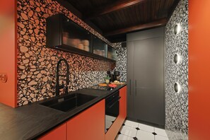 Eine moderne Küche mit schwarzem Arbeitsplatz, integriertem Spülbecken und einer Spritzschutzwand mit Steinmuster.