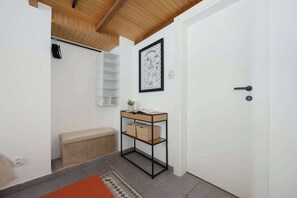 A hallway with a white door, a small bench, a shelf with baskets, and a framed map on the wall. - Charming Flat with a Mezzanine | 2 Bedrooms | Close to the City Centre (Warszawa)
