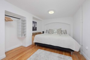 Ein Schlafzimmer mit Bett, Kleiderschrank, einer Pendelleuchte und einem gerahmten Bild an der Wand.