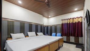 A hotel room with a large bed, a ceiling fan, and a window with curtains. - Srinivasa Residency - SVGMC (Tirupati)