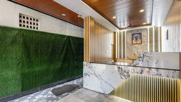 A lobby with a green wall, marble flooring, and a wooden ceiling.