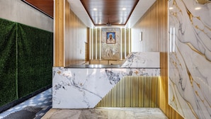A reception area with a marble counter, wooden paneling, and a green wall. - Srinivasa Residency - SVGMC (Tirupati)