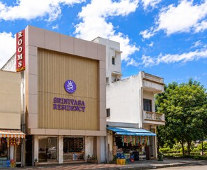 A building with a sign for 'Srinivasa Residency' and a 'ROOMS' sign on the left. - Srinivasa Residency - SVGMC (Tirupati)