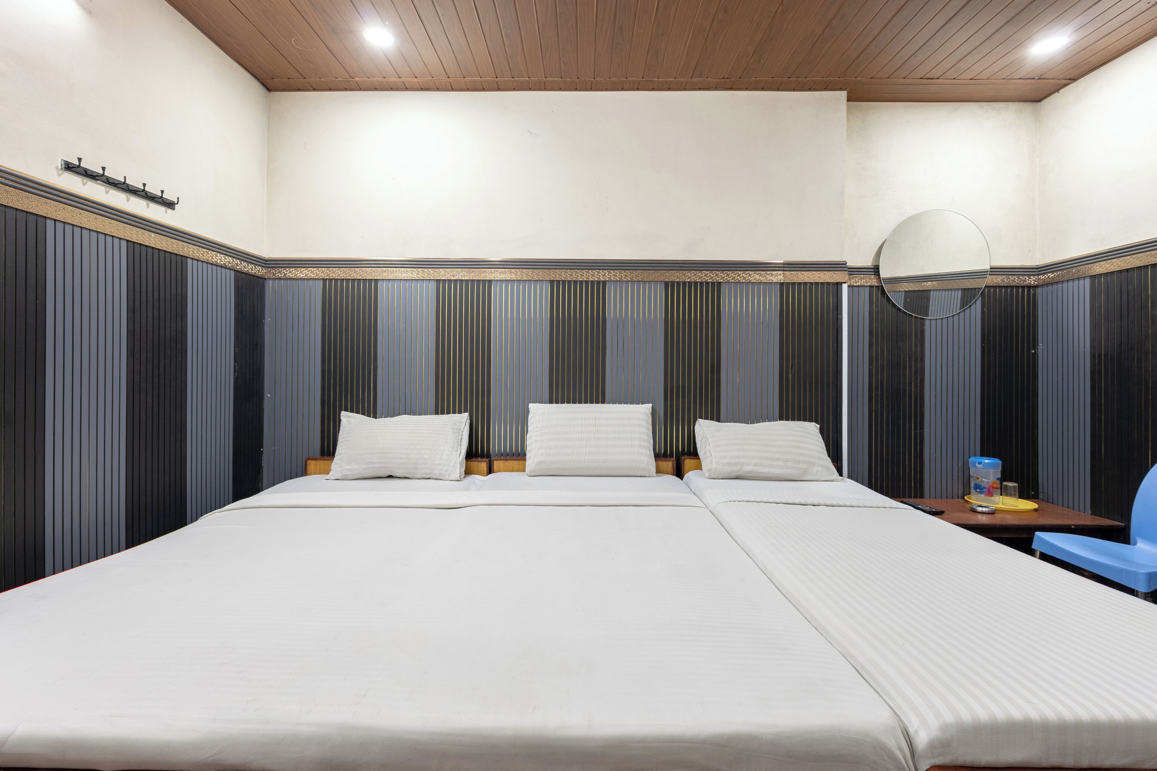 Habitación de hotel con una cama grande, una mesita de noche, una silla y un espejo.