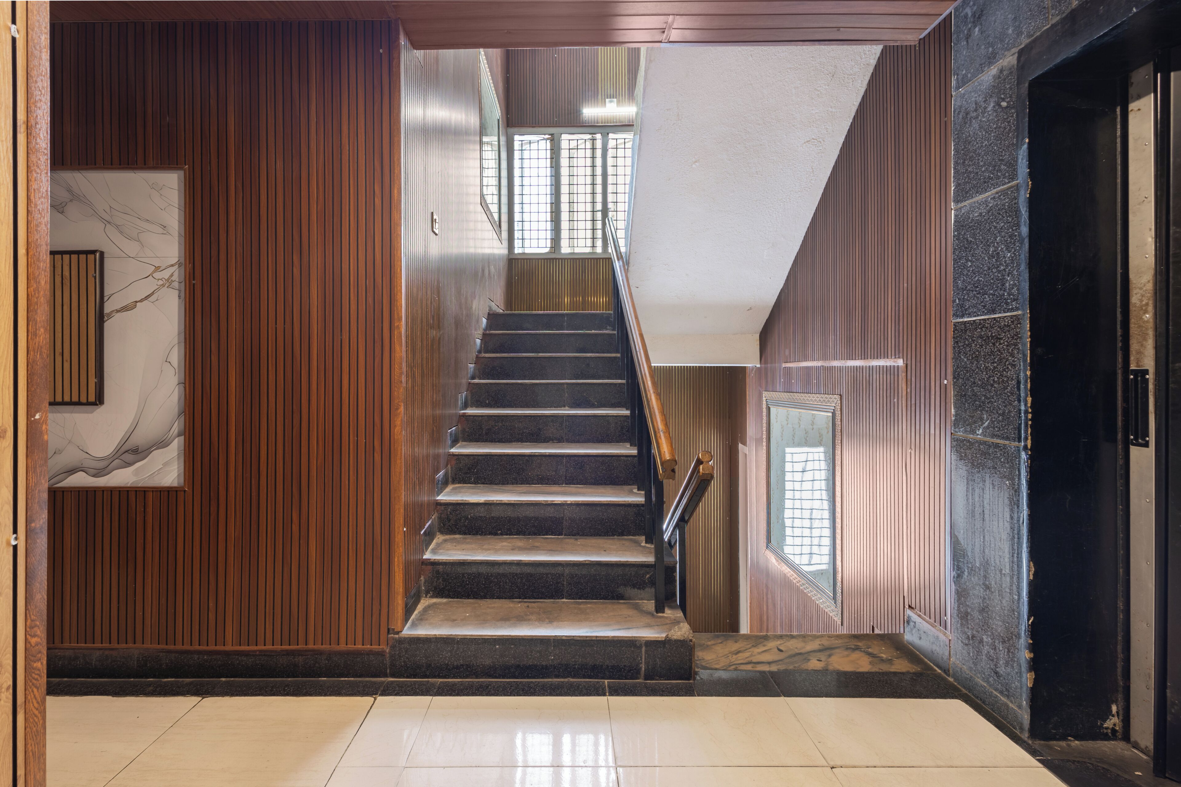 A staircase with a wooden wall on one side and a stone wall on the other, leading to an upper floor.