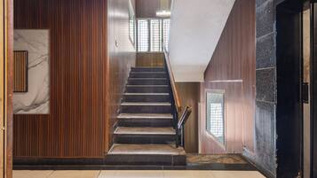 A staircase with a wooden wall on one side and a stone wall on the other, leading to an upper floor.