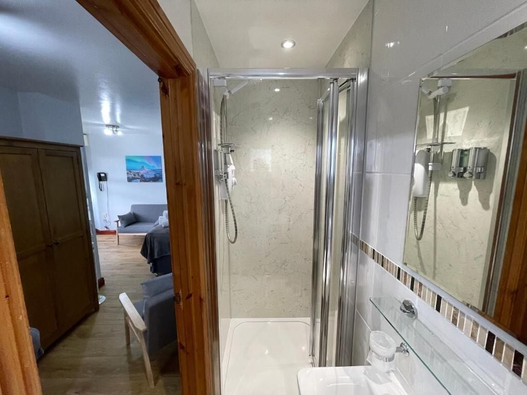 Een moderne badkamer met een douchecabine van glas, een grote spiegel en een witte wastafel.