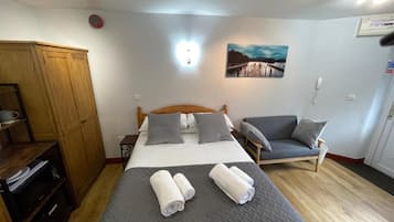 Une chambre à coucher avec un lit, deux tables de chevet, une armoire, une chaise et un tableau accroché au mur.