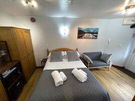 A bedroom with a bed, two bedside tables, a wardrobe, a chair, and a painting on the wall.