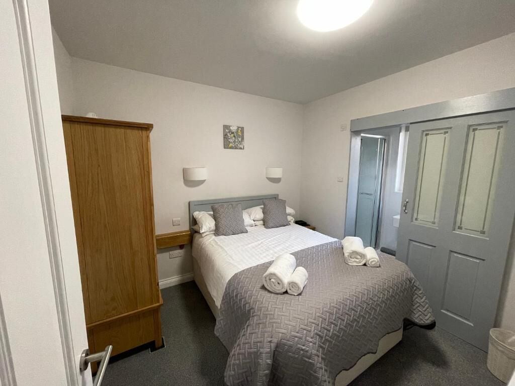 Un dormitorio con cama, armario, puerta y lámpara fijada en la pared.