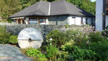 A stone building with a sloped roof, a sign indicating 'Quaysiders Club,' and a stone wall with a circular emblem.