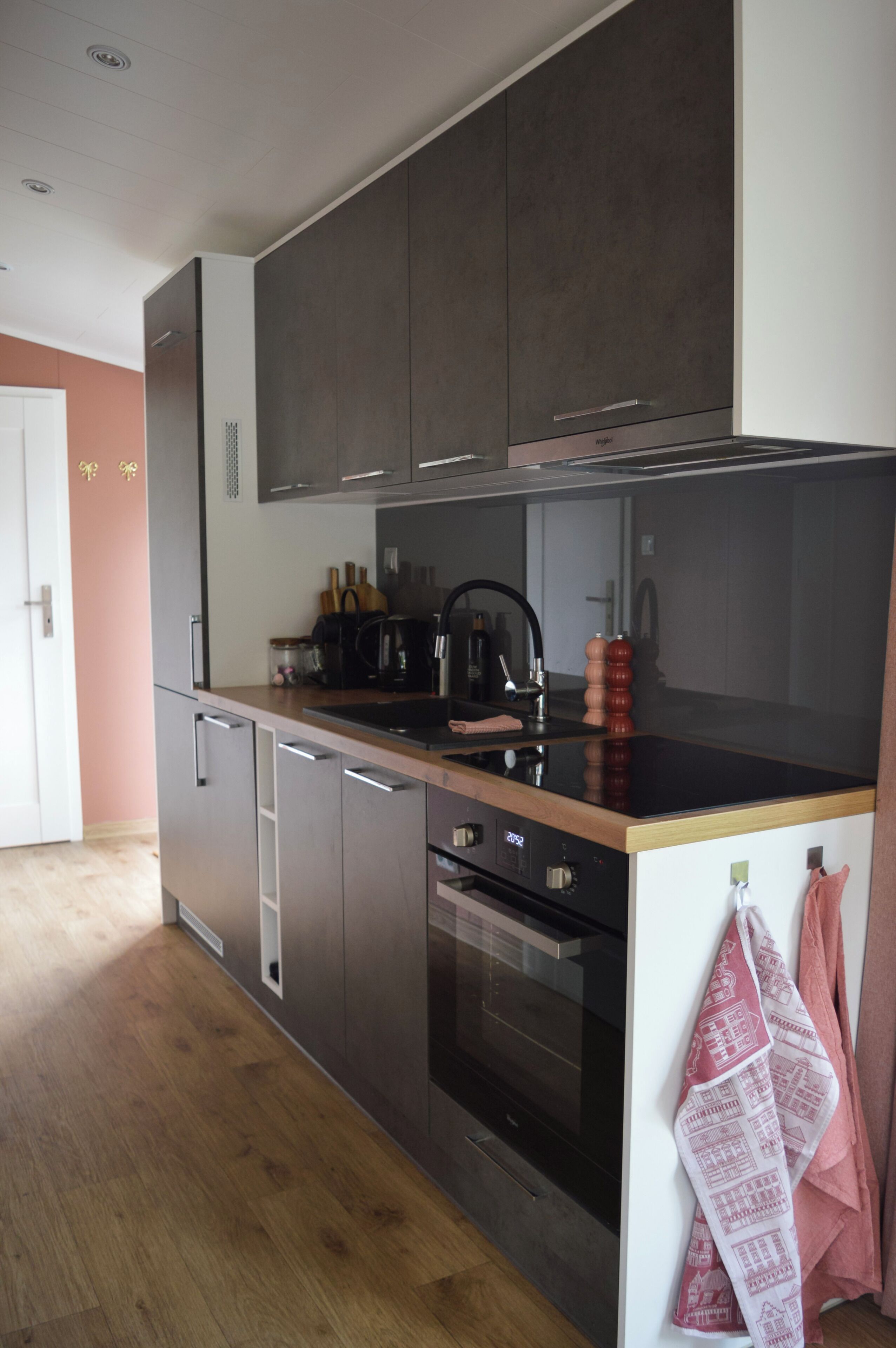 Una cocina moderna con armarios oscuros, una campana extractora de acero inoxidable y un horno empotrado.