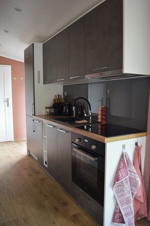 Una cocina moderna con armarios oscuros, una campana extractora de acero inoxidable y un horno empotrado.