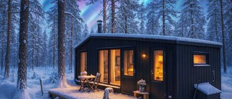 A cabin with a wooden exterior, large windows, and a small porch area.