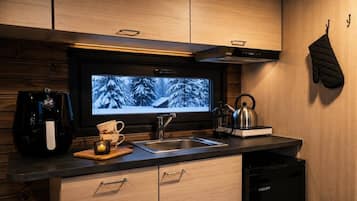 Una cocina moderna con televisor integrado, electrodomésticos de acero inoxidable y armarios de madera.
