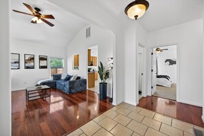 A spacious living room with hardwood flooring, a blue sofa, a coffee table, and a ceiling fan.