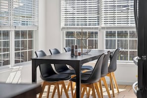 A modern dining area with a rectangular table, black chairs, and a decorative metal centerpiece.