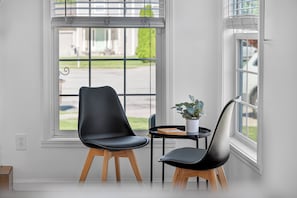 Ein Zimmer mit einem modernen Sessel, einem kleinen Tisch und einer Topfpflanze.