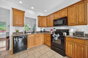 A modern kitchen with wooden cabinets, a built-in microwave, a dishwasher, and a stove.