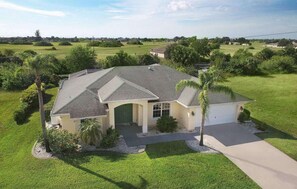 A single-story house with a sloped roof, a front garage, and a well-maintained lawn. - Villa Cimarron - Waterfront Pool Home, Kayaks & Bikes (Cape Coral)